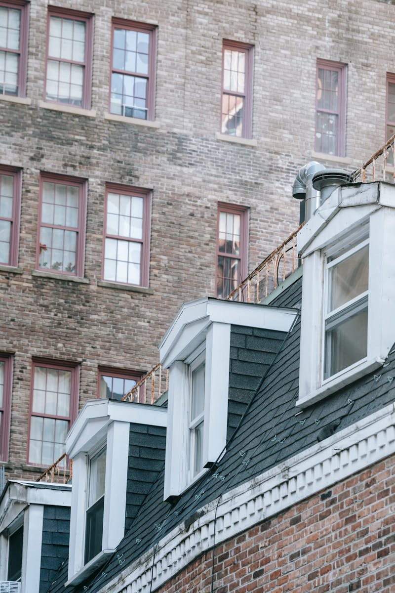Rows of attic windows at roof against shabby facade of old brick building